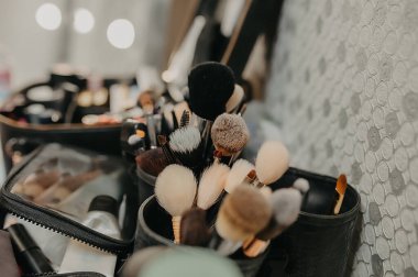 Makyaj sanatçısının masasında gölgeler ve kozmetik paletleri bulunan farklı boyutlarda makyaj fırçaları.