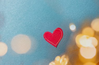 Üniformalı mavi arka planda kağıttan yapılmış parlak kırmızı çevre dostu kalp ve kenarlı ampullerden bokeh, sevgi ve duygular hakkında sevilen biri için bir kart.
