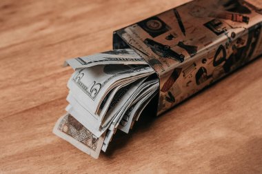 Para depolamak ve biriktirmek için bir metal kutu, bir yığın buruşuk dolar, ön planda 5 dolarlık fatura.