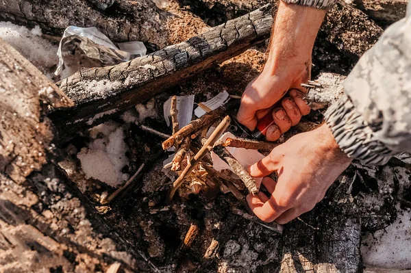 lighter in rough hands set fire to paper and logs to make a fire for camping