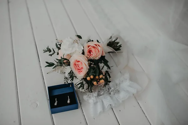 花嫁のためのスタイリッシュなアクセサリー 結婚式の日のための女性のケアと美しさのアイテムと花嫁の衣装 ホワイトゴールドダイヤモンドと牡丹のバラの花束と高価なイヤリング — ストック写真