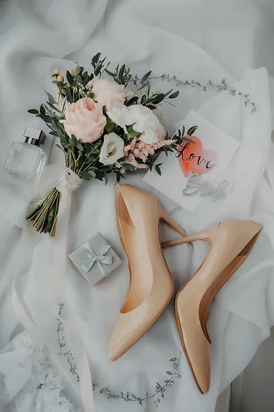 ドレスや結婚式の衣装のための花嫁のスタイリッシュなアクセサリー ベージュの特許革の靴 リングのためのシルバーボックスと白いチュールの背景に牡丹のバラのスタイリッシュな花束 — ストック写真