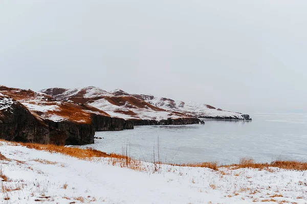 amazing northern landscape, ice sea in a round unusual ice of blue color against the background of hills and grottoes in snow and ice