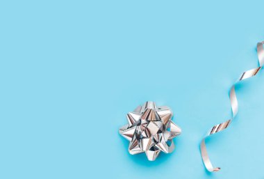 Gümüş folyo yay ve mavi arka planda gümüş kurdele. Selamlama için maket