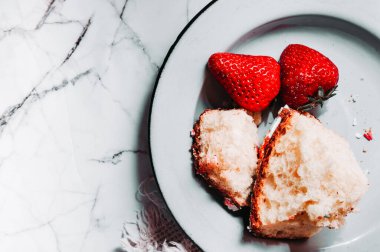 Ev yapımı basit kahvaltı taze çilekleri ve beyaz mermer üzerinde mavi-gri metal bir tabakta ev yapımı taze ekmek.