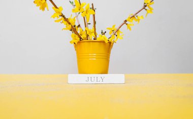 Haziran 'ı küçük metal bir kovayla süslemek için üzerinde bir buket bahar çiçeği olan bir tahta parçasının üzerine yazdım. Daimi ahşap takvim. Haziran ayı.