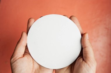 Pembe arka planda açık tenli ellerde bir yazı veya logo için beyaz boş bir daire