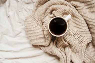 Siyah kahve, örgü bej süveter, buruşuk yatak, üst manzara, tek renkli rahat kahvaltı resmi.