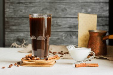 Kahve çekirdekleri ve tarçın çubukları, süt sürahisi, Türk kahve demliği açık ahşap masada.
