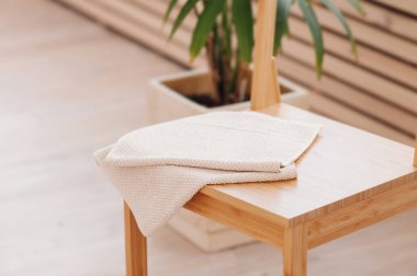 Tahta banyo masasına katlanmış doğal bej havlu. Doğal malzemeler kullanarak banyo dekoru oluşturuyorlar. Yenilemede minimalizm