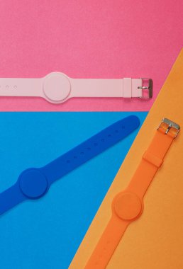 Turuncu, mavi ve pembe silikon saat. Arkaplanda da manyetik sensör var. Monokrom görüntüsü. Sağlıklı yaşam tarzınız, sağlığınıza dikkat edin.