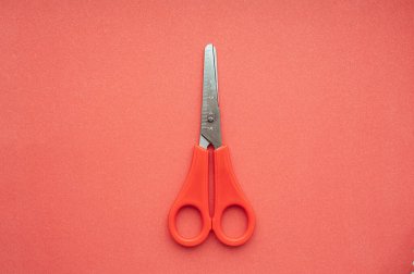 Monokrom minimalistik resim. Metal makas ve bir ölçüm cetveli ve kırmızı saplı düz kırmızı zemin.