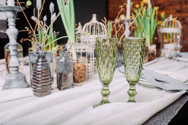 Romantik bir randevu için çevre dostu servis masasında iki yeşil içecek bardağı. Canlı bitkiler ve dallarla dolu gizemli bir bahar tarzında masa..