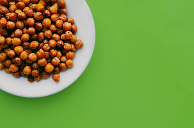 Sağlıklı beslenme bayrağı. Temiz yeşil arka planda beyaz tabakta kızarmış nohutlar hazır..