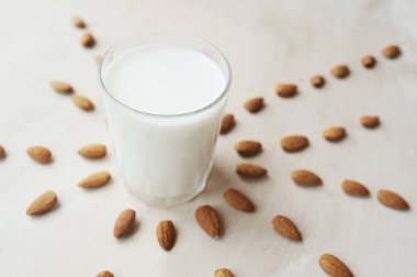 Çok güzel yayılmış bademlerin arka planında süt dolu şeffaf bir kupa. Badem sütü, üst manzara