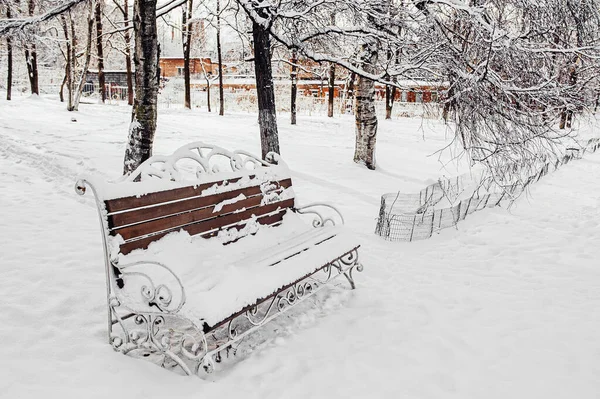 Very beautiful wood and metal bench on a winter snow day. Fresh fluffy untouched snow in the city Park.