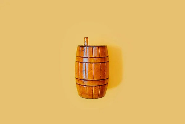 Wooden old vintage orange barrel with a lid on a smooth clean yellow background. Postcard on the theme of the Barrels holiday fastelavn