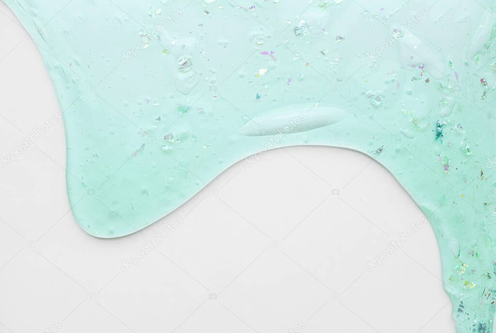 Mint slime with sparkles and oxygen bubbles flows down on a clean white background for the inscription. Ready-made layout on the theme of cosmetics and skin care