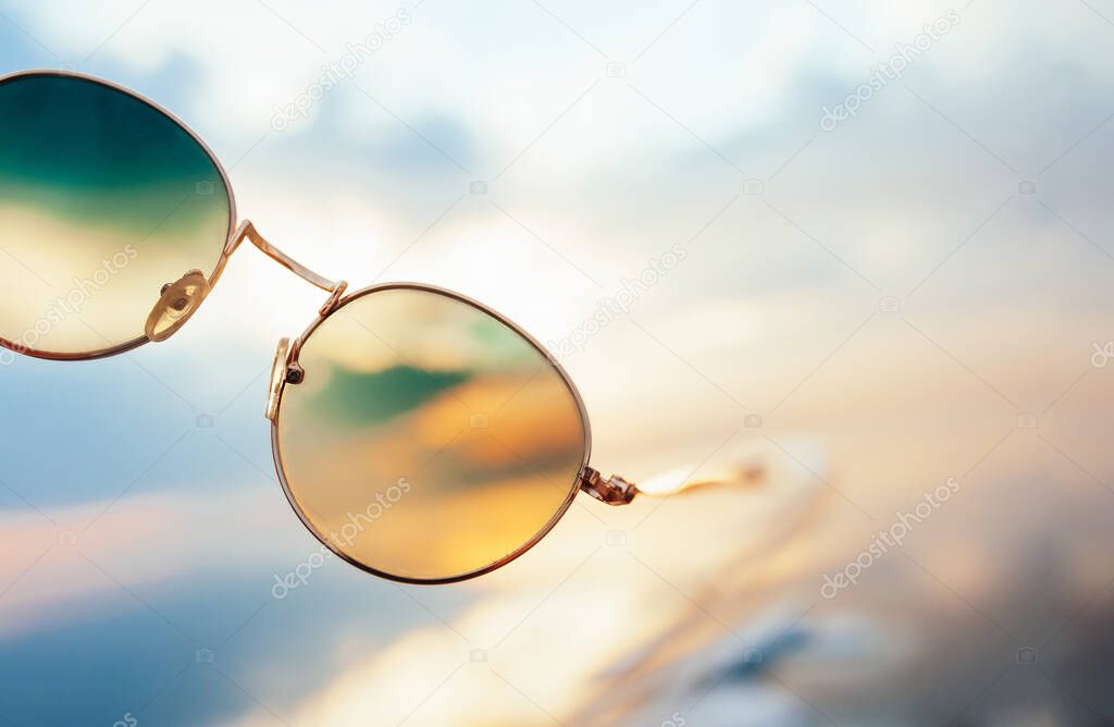 An unusual and bright colorful image of the sunset through gold metal sunglasses. Layout for holidays and travel.