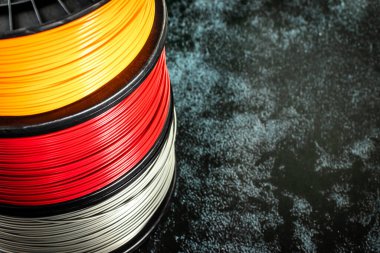 Filament for 3d printing. Bright thermoplastic of neon orange, color. Reel horizontal view. clipart
