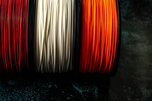 Three coils of filament for 3d printing. Bright thermoplastic of red, white smd orange colors. — Stock Photo, Image