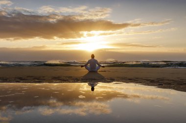 Yoga meditasyon silueti lotus gün doğumu plajı, yoga poziyonundaki insanın su yansıması, farkındalık konsepti.