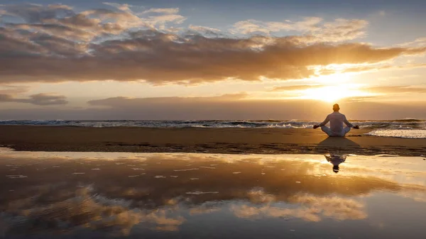 Yoga meditazione silhouette loto alba spiaggia, riflesso dell'acqua dell'uomo in posa yoga, consapevolezza concetto di benessere — Foto Stock