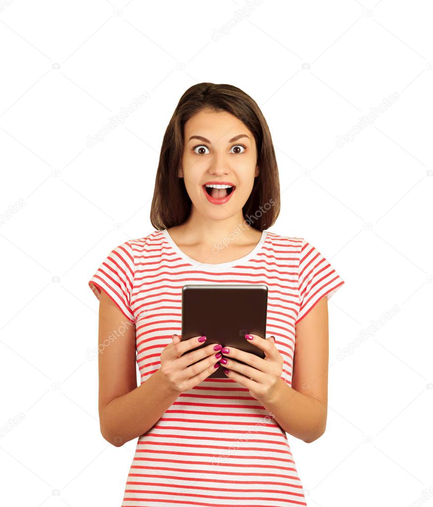 Portrait of surprised and impressed woman with widened eyes and opened mouth, stunned because of something she sees on screen of tablet. emotional girl isolated on white background.