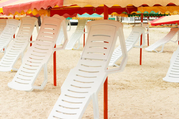 folded chaise lounges and umbrellas on the sandy beach.