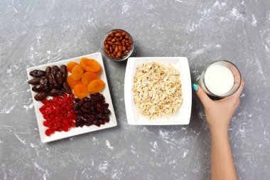 Kız süt yulaf ezmesi dökmek için aldı. Gri bir arka planda en iyi görünüm yararlı ve sağlıklı bir kahvaltı.