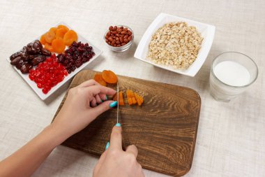 Kız ona kahvaltı hazırlıyor. Kesme Kuruyemiş haline yulaf lapası bir kesme tahtası üzerinde. Yararlı ve sağlıklı bir kahvaltı. açık renkli.