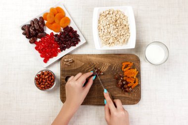 Kız ona kahvaltı hazırlıyor. Kız onun tarihi meyve yulaf lapası kesme tahtası olarak keser. Yararlı ve sağlıklı bir kahvaltı. açık renkli.