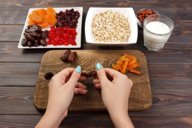 Kız ona kahvaltı hazırlıyor. Kız onun tarihi meyve yulaf lapası bir kesme tahtası üzerinde temizler. Yararlı ve sağlıklı bir kahvaltı. koyu ahşap arka plan, üstten görünüm.