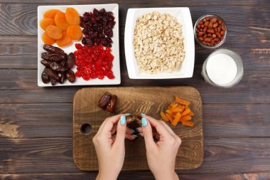 Kız ona kahvaltı hazırlıyor. Kız onun tarihi meyve yulaf lapası bir kesme tahtası üzerinde temizler. Yararlı ve sağlıklı bir kahvaltı. koyu ahşap arka plan, üstten görünüm.