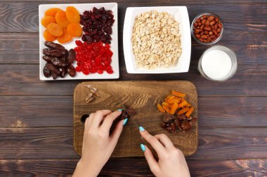 Kız ona kahvaltı hazırlıyor. Kız onun tarihi meyve yulaf lapası kesme tahtası olarak keser. Yararlı ve sağlıklı bir kahvaltı. koyu ahşap arka plan, üstten görünüm.