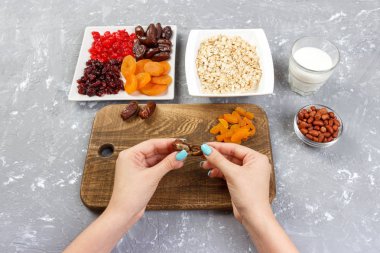 Kız ona kahvaltı hazırlıyor. Kız onun tarihi meyve yulaf lapası bir kesme tahtası üzerinde temizler. Gri bir arka planda en iyi görünüm yararlı ve sağlıklı bir kahvaltı.