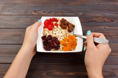 Kız onu müsli kahvaltı için pişirdim. Kız kilo vermek ve bir diyet sürdürmek yulaf püresi yiyor. Yararlı ve sağlıklı bir kahvaltı. koyu ahşap arka plan, üstten görünüm.