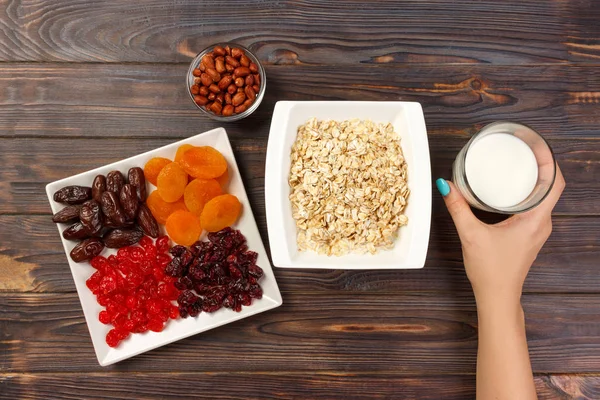 Kız süt yulaf ezmesi dökmek için aldı. Yararlı ve sağlıklı bir kahvaltı. koyu ahşap arka plan, üstten görünüm.