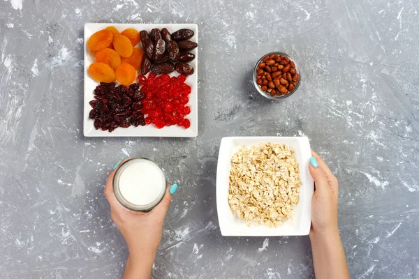Kız süt yulaf ezmesi dökmek için aldı. Gri bir arka planda en iyi görünüm yararlı ve sağlıklı bir kahvaltı.