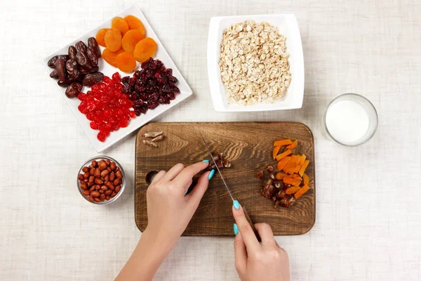 Kız ona kahvaltı hazırlıyor. Kız onun tarihi meyve yulaf lapası kesme tahtası olarak keser. Yararlı ve sağlıklı bir kahvaltı. açık renkli.