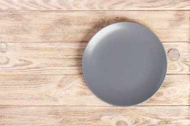 Ahşap arka plan üzerinde kopya alanı gri boş yuvarlak plaka ile üstten görünüm.