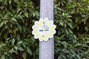 yeşil bir arka plana sahip bir parkta bir çiçek şeklinde yok Sigara İçilmez işareti.