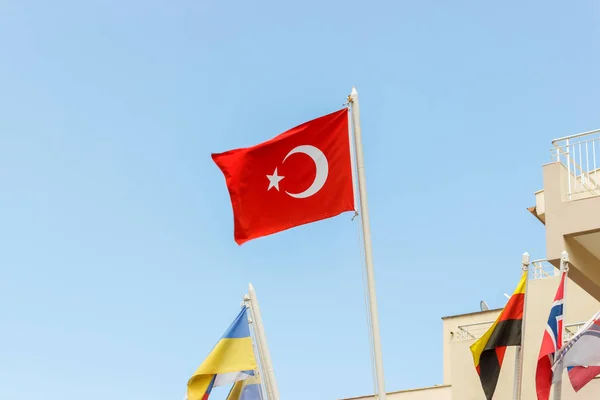 The national flag of Turkey blowing in the wind against a blue sky.