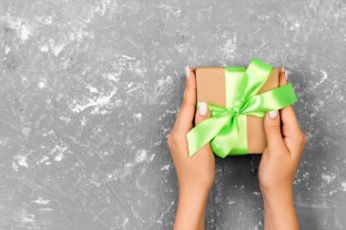 Gri arka plan, üstten görünüm önemli gün için elinde yeşil Fiyonklu hediye kutusu.