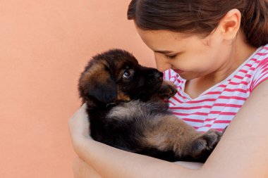 Holding ve siyah köpek yavrusu gözlerine bakarken güzel kadın.