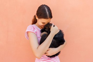 Genç kadın bir küçük şirin köpek yavrusu sarılma sahiptir.