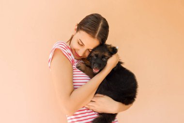 Genç güzel kadın ile siyah bir köpek yavrusu. Holding ve köpeğini sarılma güzel kadın.