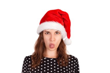 Memnun esmer kadın modeli, dil, biriyle tahriş gösterir iğrenç ifade vardır. Noel Baba'ya duygusal kız beyaz arka plan üzerinde izole Noel şapka.