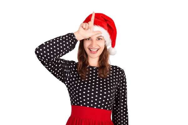 俏皮的疯狂的妇女的肖像在礼服牵手显示字母 做失败者的手势和微笑 在圣诞老人圣诞节帽子查出的情感女孩在白色背景 假日概念 — 图库照片
