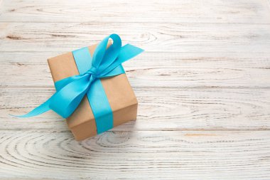 Güzel hediye kutusu beyaz ahşap masa üzerinde mavi bir yay ile. üstten görünüm.